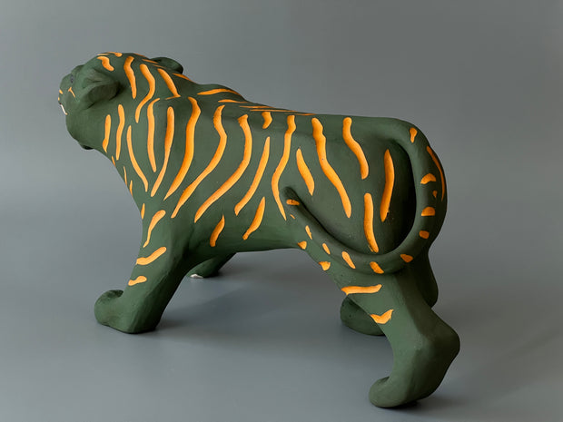 Matte finished ceramic sculpture of a green tiger with orange stripes, it is in a prowling stance with its mouth in a slightly growl.