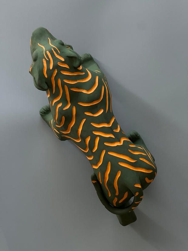 Matte finished ceramic sculpture of a green tiger with orange stripes, it is in a prowling stance with its mouth in a slightly growl.