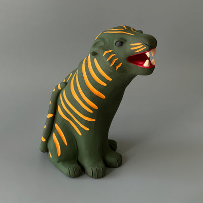 Matte finish ceramic sculpture of a green tiger with orange stripes, sitting on its hindlegs and with an open mouth smile