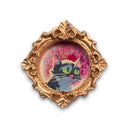 Painting of a small, cute cartoon cat against a colorfl sky. Framed in a tiny gold, ornately designed frame.