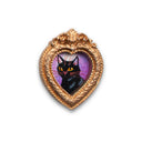 Painting of a small, cute cartoon cat against a colorful sky. Framed in a tiny gold, ornately designed frame.