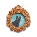Painting of a small, cute cartoon cat against a colorful sky. Framed in a tiny gold, ornately designed frame.