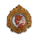An ornate gold-framed circular artwork featuring a whimsical, textured painting of a red-skinned demon or goblin with green eyes and a mischievous expression, set against a plain white background.
