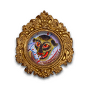 A circular framed artwork featuring a painted monkey face with red eyes and a red grin, set within an ornate gold baroque-style frame on a white background.