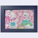 A framed artwork featuring three cute, stylized cartoon characters in a pink floral pattern, set in a dark navy blue frame against a light gray background.