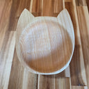 Wooden bowl shaped like a cat's face on a wooden surface