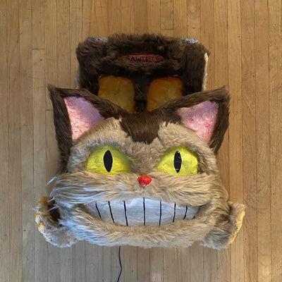 Catbus shaped paper mache and fur wall hanging sculpture, smiling and with lighting elements.
