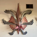 Decorative wall art of a monster creature's face on a plain wall.