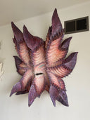 Very large paper mache sculpture of a monster's head with many pointed edges, akin to a leaf with a menacing face.