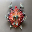 Colorful paper mache mask of a monster's head, without any facial features and only 4 claws as a beak mouth.