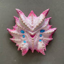 Mask made of paper mache of a pink and white multi-eyed monster with many spikes coming off its face.