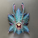 Paper mache sculpture of a monster's head without facial features aside from an open mouth beak.