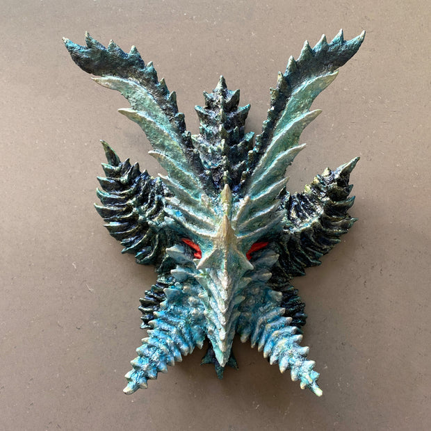 Metallic Kaiju mask sculpture - blue with many ridges on its surface and horns.