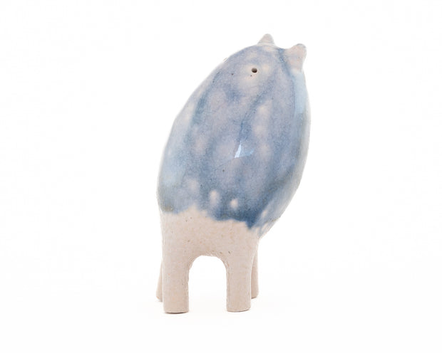 Ceramic sculpture of a small blue and white creature with small ears and eyes and no arms but 4 legs.