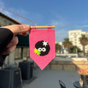 Pink felt banner with a character design held by a hand against a blurred outdoor background