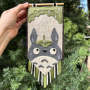 Handmade banner with a character design held in front of green foliage