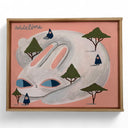 Framed artwork of a large white rabbit with blue eyes, it lays wiith its body curved into itself and has small figures atop its back in a forest setting.