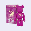Pinkish purple bearbrick figure with a matching box on a light purple background