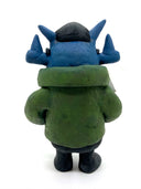 Clay sculpture of a blue robot wearing glasses with a black baseball cap, green army jacket and holding a camera in both hands and a magazine in between its arm.