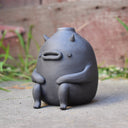 Gray vase with a cute monster face and arms and legs.