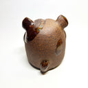 Ceramic sculpture of a cute, brown bulldog with its paws on its cheek and a rounded bottom without legs.