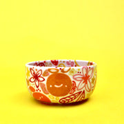 Small ceramic bowl, white with many paintings of floral patterns and fruits in warm colors such as orange, red, yellow and pink.