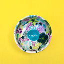 Small ceramic bowl, white with many paintings of floral patterns and fruits in cool tones such as green, blue and purple.