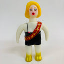 Toy figure with yellow hair, red nose, and black outfit on a white background