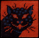 Needlepoint artwork of a black and blue cat creature, looking head on and smiling with red eyes and a smile. Seen from the neck up.