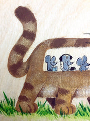 Painting on exposed wooden panel of a brown cat shaped like a bus, with a blue drivers cap and mice as passengers within. It walks atop grass.