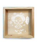 Backside of wood panel with white marker illustration of a character sticking her tongue out with her cat.