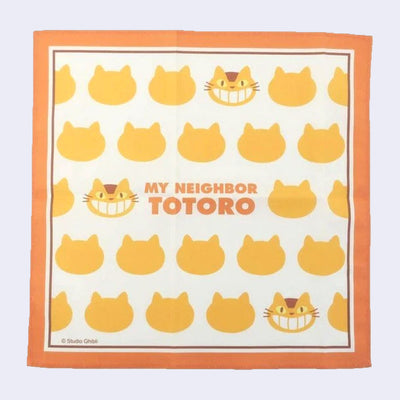 Handkerchief with orange border and repeating patterns of Catbus heads, with text that reads "My Neighbor Totoro" in the center in orange font.