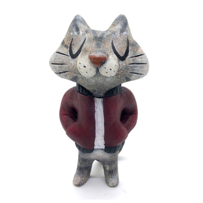 Sculpture of a cartoon gray cat, with closed eyes and a calm expression. It stands like a human and wears a burgundy jacket with its hands in its pockets.