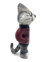 Sculpture of a cartoon gray cat, with closed eyes and a calm expression. It stands like a human and wears a burgundy jacket with its hands in its pockets.