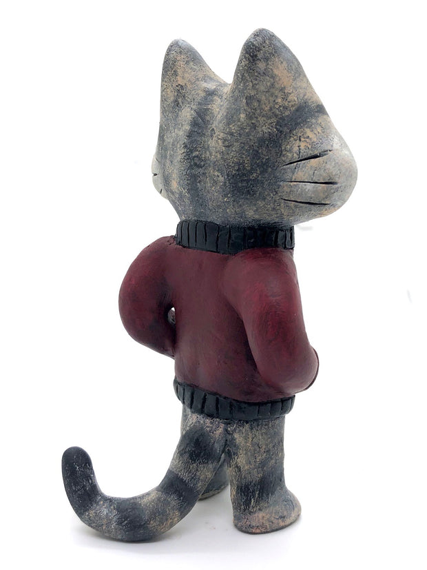 Sculpture of a cartoon gray cat, with closed eyes and a calm expression. It stands like a human and wears a burgundy jacket with its hands in its pockets.