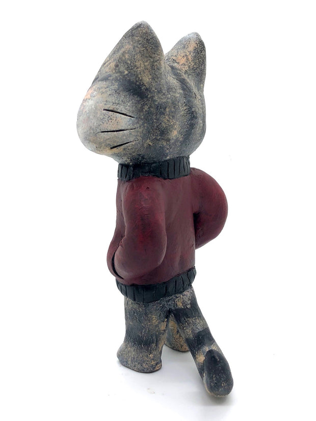 Sculpture of a cartoon gray cat, with closed eyes and a calm expression. It stands like a human and wears a burgundy jacket with its hands in its pockets.