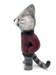 Sculpture of a cartoon gray cat, with closed eyes and a calm expression. It stands like a human and wears a burgundy jacket with its hands in its pockets.