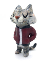 Sculpture of a cartoon gray cat, with closed eyes and a calm expression. It stands like a human and wears a burgundy jacket with its hands in its pockets.