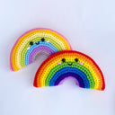 2 crocheted rainbows with simple, cute smiling faces with pink blushing cheeks. One rainbow consists of traditional colors and the other consists of pastel rainbow colors.