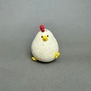 Ceramic figurine of a small white chicken with an opening at the top of its head for flowers.