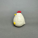 Ceramic figurine of a small white chicken with an opening at the top of its head for flowers.