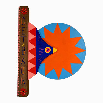 Die cut painted wooden sculpture of a vertical post that reads "Get Back" in stylized font. Coming out of the right side of the post is a blue bird, with a large round blue circle. Within the circle is a large orange starburst.