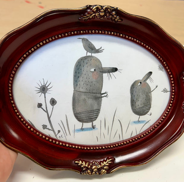 Illustration of 2 gray cartoon moles, walking on hind legs and with their arms extended out. A bird sits atop one of the mole's head.