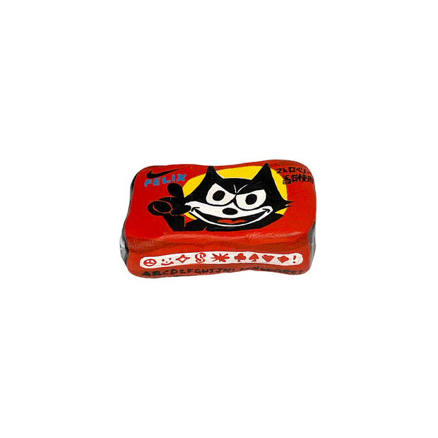 Small sculpture of a wrapped piece of square gum with a photo of Felix the Cat on it, looking happy but menacing.