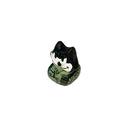 Small figurine of a black cat with a white face on a tiny green tank against a white background