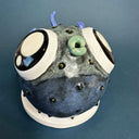 Ceramic sculpture of a small, blowfish with very very large eyes. It is blue with blue fins and green lips.