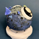 Ceramic sculpture of a small, blowfish with very very large eyes. It is blue with blue fins and green lips.