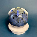 Ceramic sculpture of a small, blowfish with very very large eyes. It is blue with blue fins and green lips.