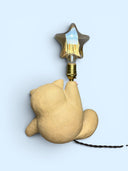 Matte finished ceramic lamp shaped like a very chubby cat with its leg up in the air and a star shaped light bulb at the top of its raised foot.
