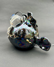 Ceramic sculpture with a pearlescent finish of a round bodied angler fish, with giant bulbous eyes and a blue antenna overhead.